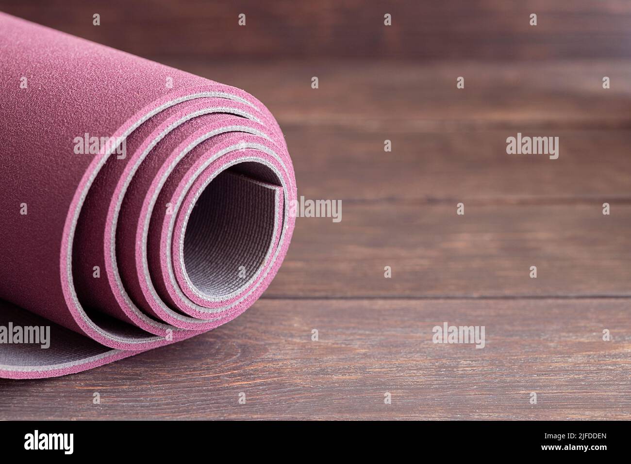 Gerollte Yogamatte auf Holzboden, Konzept für den Start des Ashtanga Yoga. Speicherplatz kopieren. Stockfoto