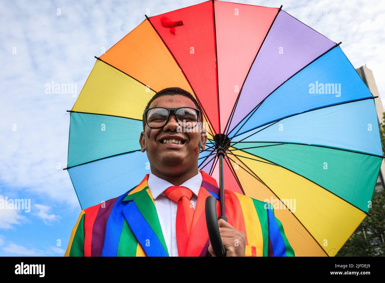 London, Großbritannien. 02.. Juli 2022. Ein Teilnehmer posiert stolz mit dem Regenbogenschirm während des Aufbaus in der Park Lane. Teilnehmer und Zuschauer haben Spaß auf der Route der Pride in London 2022 Parade. Die Parade führt dieses Jahr vom Hype Park entlang Piccadilly nach Whitehall. Die Pride-Bewegung und die LGBT-Gemeinschaft erinnern an 50 Jahre, seit die erste Pride im Vereinigten Königreich stattfand. Kredit: Imageplotter/Alamy Live Nachrichten Stockfoto