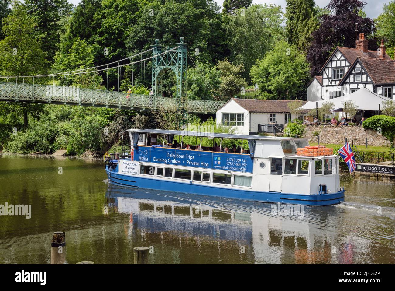 Ein Ausflugsboot auf dem Fluss Severn, das sich der Port Hill Suspension Bridge, Shrewsbury, Shropshire, nähert Stockfoto