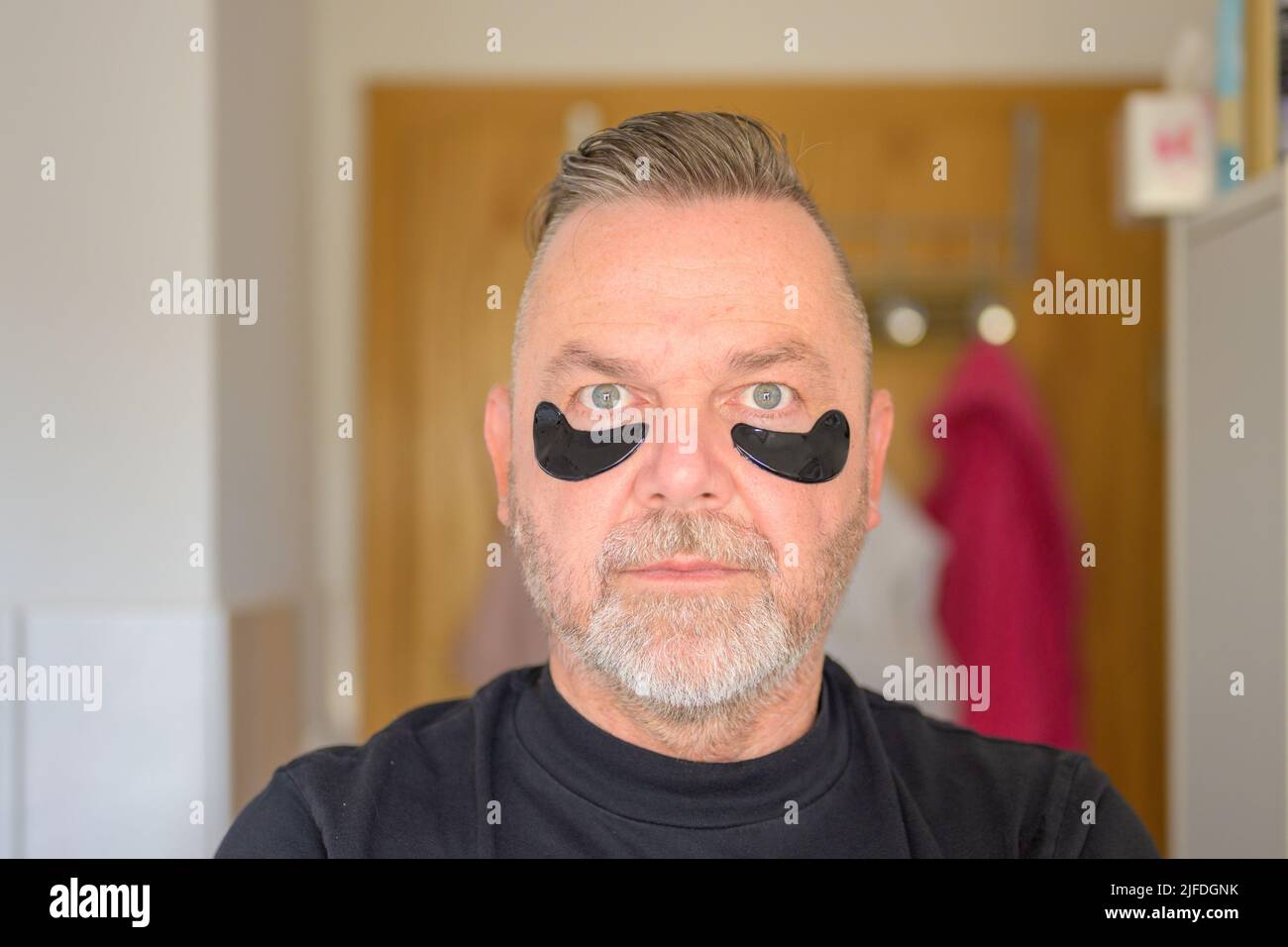 Senior Mann in einem Hautpflege- und Anti-Aging-Konzept mit Gel Hydratiin Flecken auf den Augen Stockfoto
