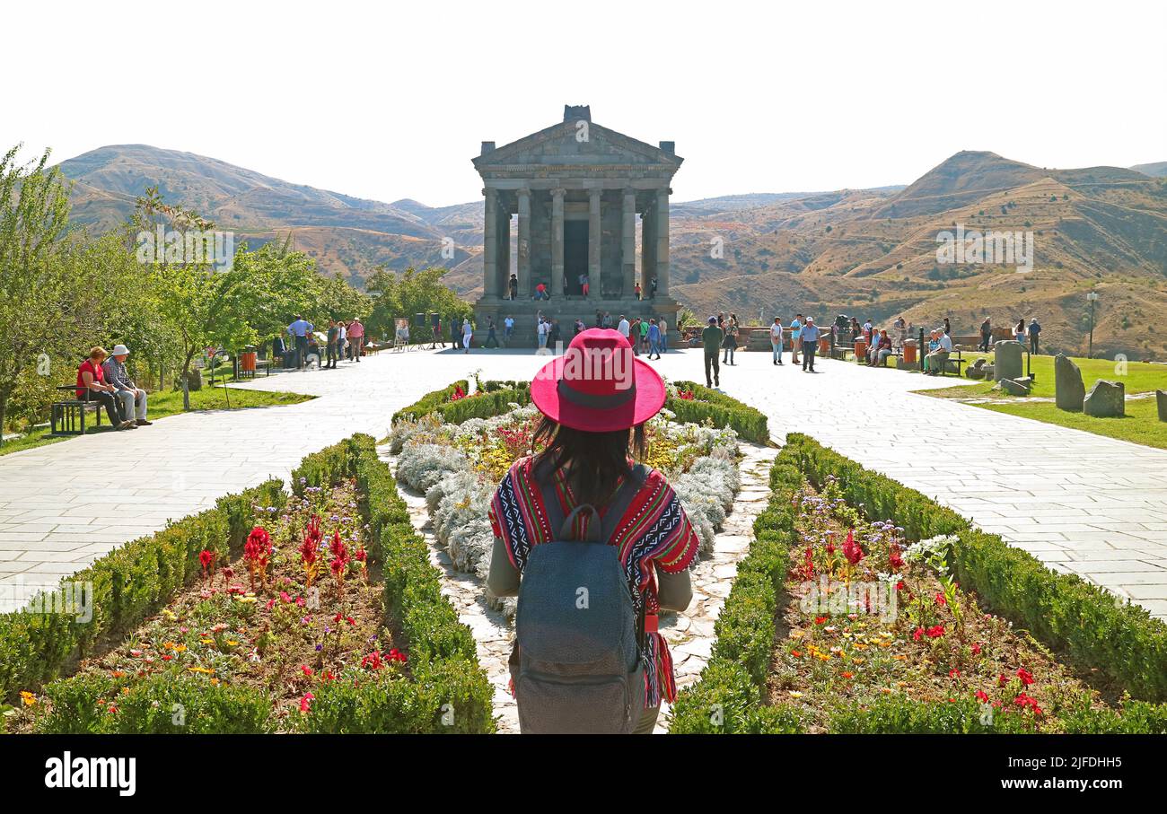 Weibliche Besucherin mit Blick auf die wunderschöne Architektur des Garni-Tempels, der sich auf dem Hügel der Provinz Kotayk, Armenien, befindet Stockfoto