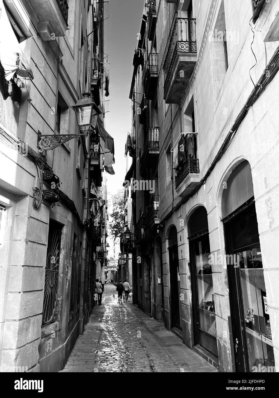 Eine vertikale Graustufenaufnahme einer schmalen Straße zwischen zwei Gebäuden Stockfoto