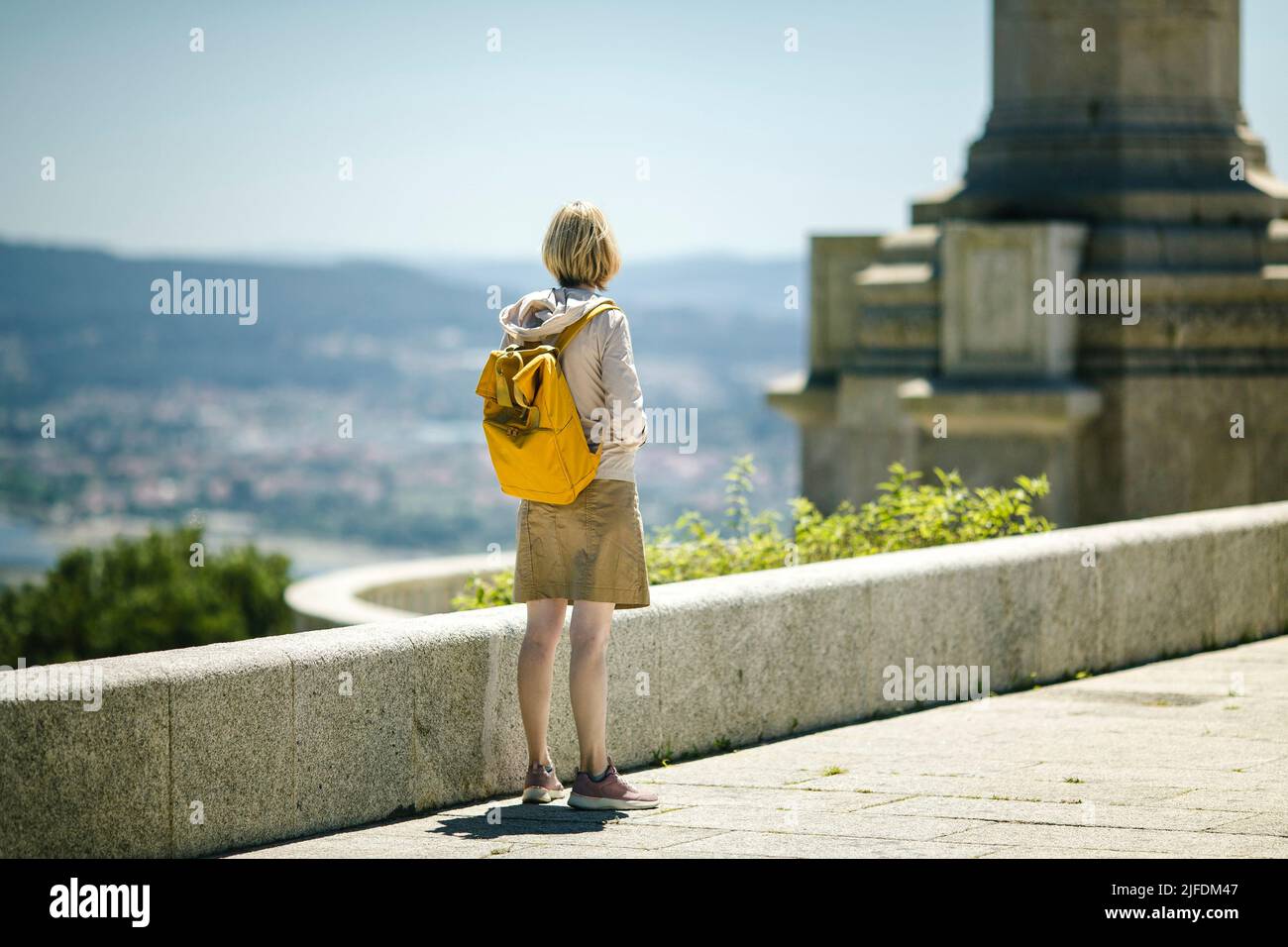 Eine Backpacker-Frau, die auf einem Aussichtspunkt steht. Rückansicht. Stockfoto