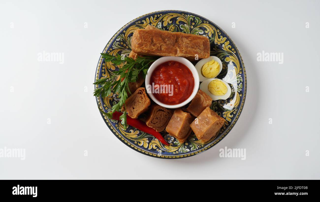 Jachnun oder Jahnun, jemenitisches jüdisches Gebäck, serviert mit frisch geriebenen Tomaten und gekochtem Ei und Zhug, aus den Adeni-Juden, und traditionell Stockfoto