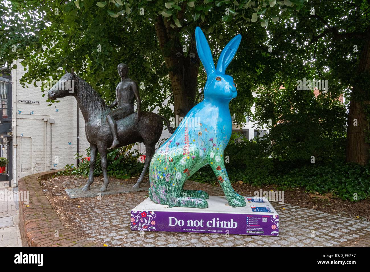 Hares of Hampshire Art Trail im Stadtzentrum von Winchester im Sommer 2022, England, Großbritannien. Bunte Hase Skulptur neben der Pferd und Reiter Statue. Stockfoto