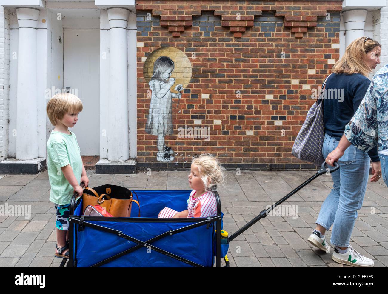 Ein Wandgemälde von Hendog, einem anonymen Künstler, das ein junges Mädchen zeigt, das Blütenblätter einer Blume pflückt, in Winchester, Hampshire, Großbritannien. Stockfoto