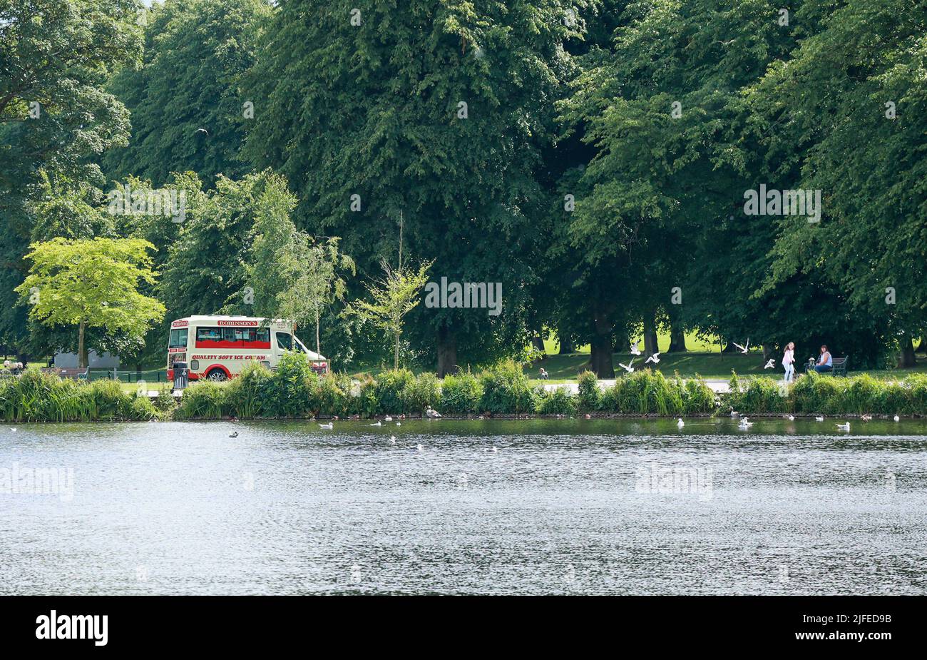 Lurgan Park, Lurgan, County Armagh, Nordirland, Großbritannien. 02. Juli 2022. Wetter in Großbritannien – warm und sonnig, wenn Lücken in einem grau bewölkten Himmel erscheinen. Ein angenehmer Nachmittag mit einem Eiswagen für diejenigen am Parksee. Kredit: CAZIMB/Alamy Live Nachrichten. Stockfoto