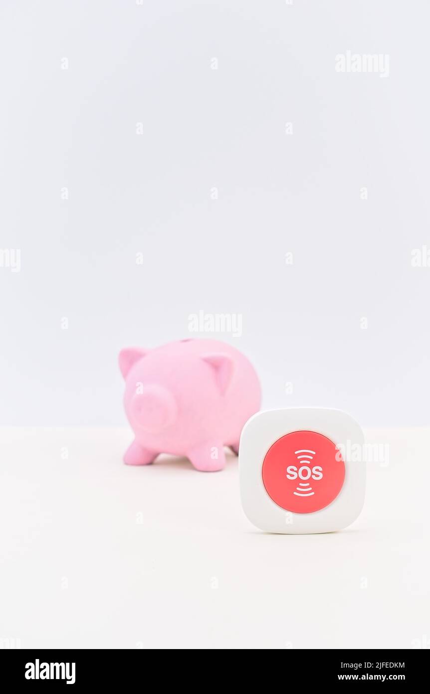 Rote SOS-Hilfetaste mit Sparschwein auf einem weißen Schreibtisch – Konzept für Inflation und Rezession Stockfoto