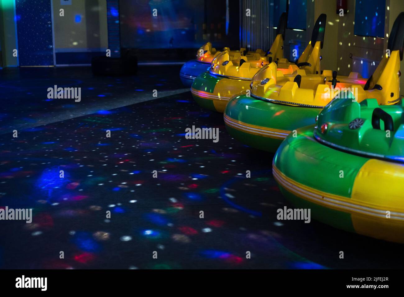 Runde batteriebetriebene Stoßfängerautos in einem dunklen Raum mit blinkenden Lichtern. Vergnügungspark. Kinderparty-Attraktion. UFO und Raum Party Thema. Stockfoto
