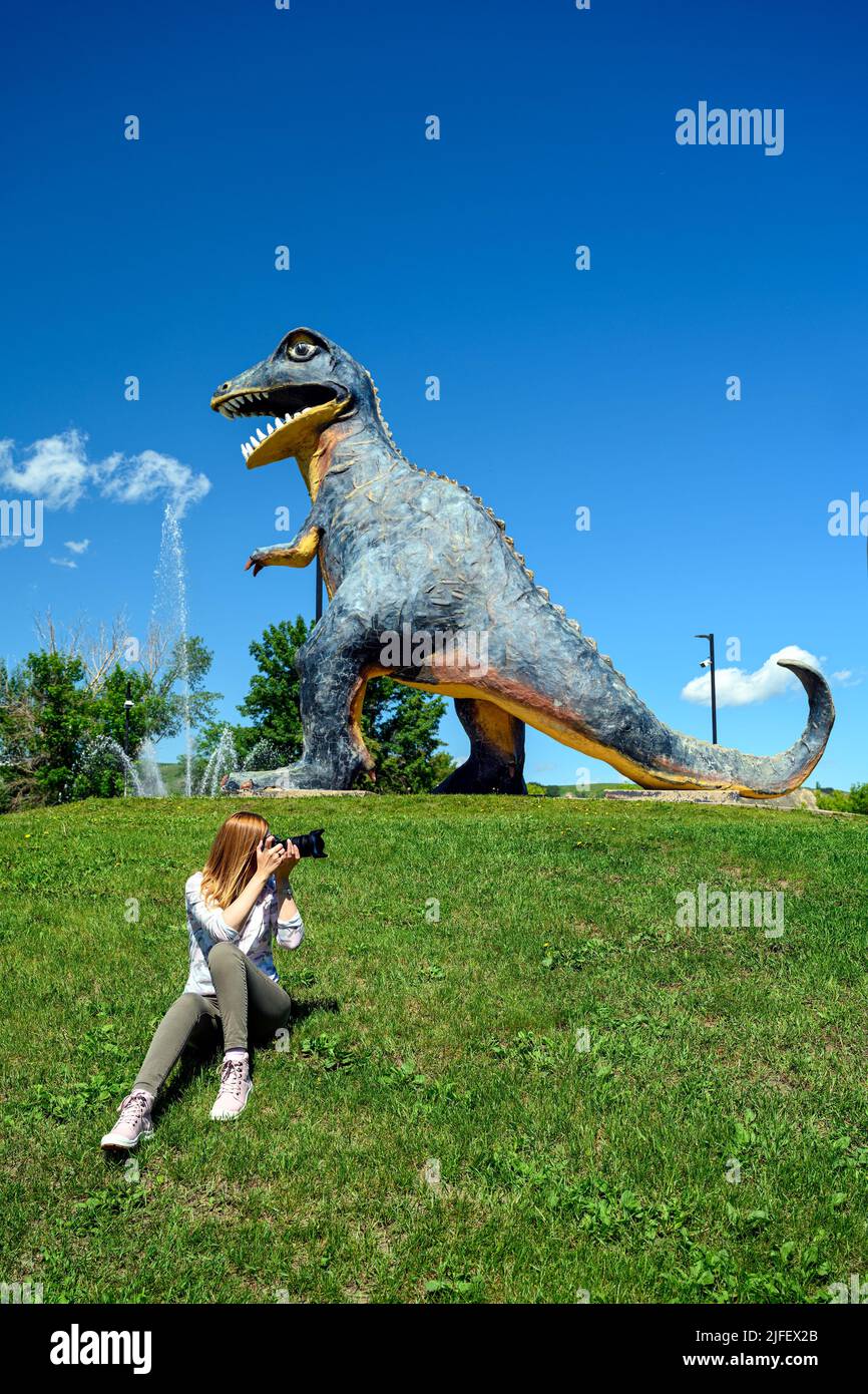 Touristenfrau, die Fotos von Thyra macht, der riesigen Dinosaurierstatue in Drumheller, der Dinosaurierhauptstadt der Welt, Alberta, Kanada Stockfoto