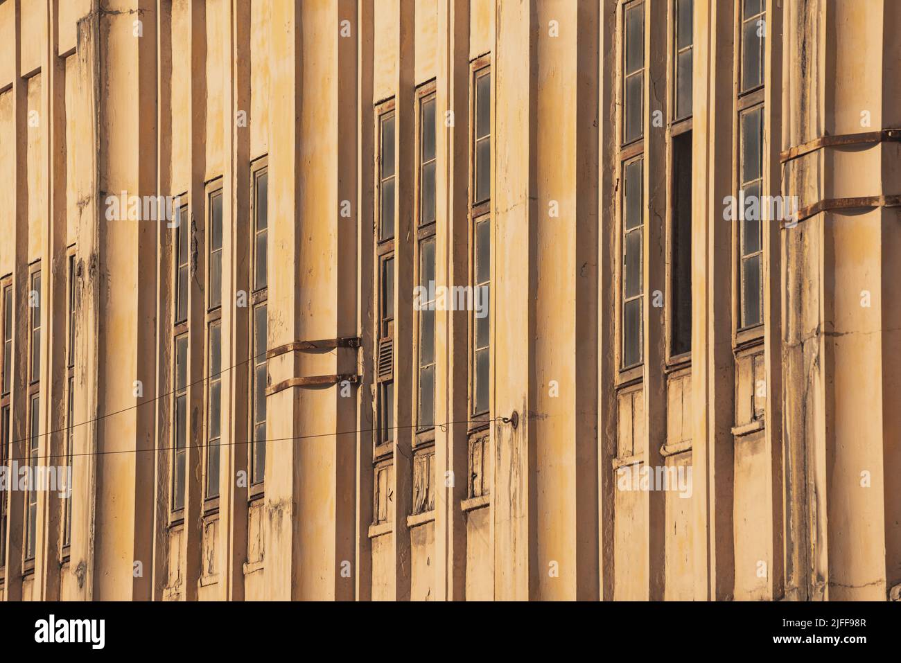 Schmale vertikale Fenster einer jahrhundertealten Fabrik. Nahaufnahme, historische Industriearchitektur. Vintage-Hintergrund Stockfoto
