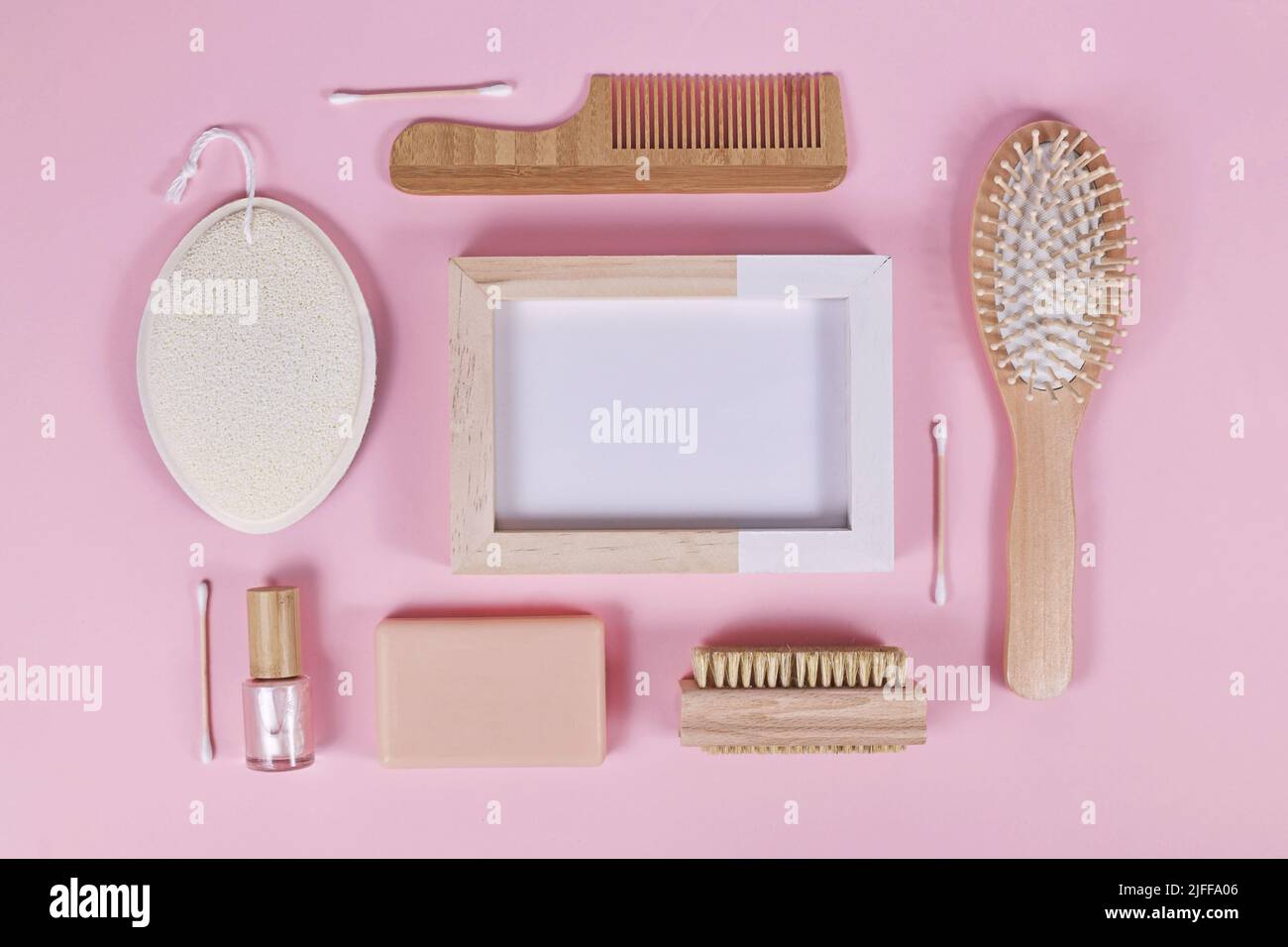 Umweltfreundliche Schönheits- und Hygieneprodukte aus Holz wie Kamm und Seife auf rosa Hintergrund angeordnet Stockfoto