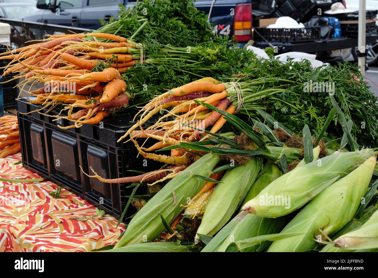 Auf dem Montgomery Alabama Farmers Market werden frischer Mais und Karotten an einem frischen Gemüse- und Erzeugerstand von einem lokalen Bauern verkauft. Stockfoto