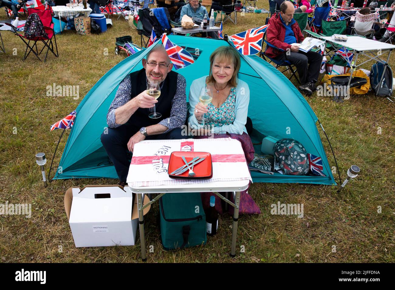 Woodstock, Oxfordshire, Großbritannien. 2.. Juli 2022. Paar in einem winzigen Zelt mit Union Jack und Red Ensign bei einem Drink. Battle Prom Picknick-Konzerte. Blenheim Palace. Vereinigtes Königreich. Quelle: Alexander Caminada/Alamy Live News Stockfoto