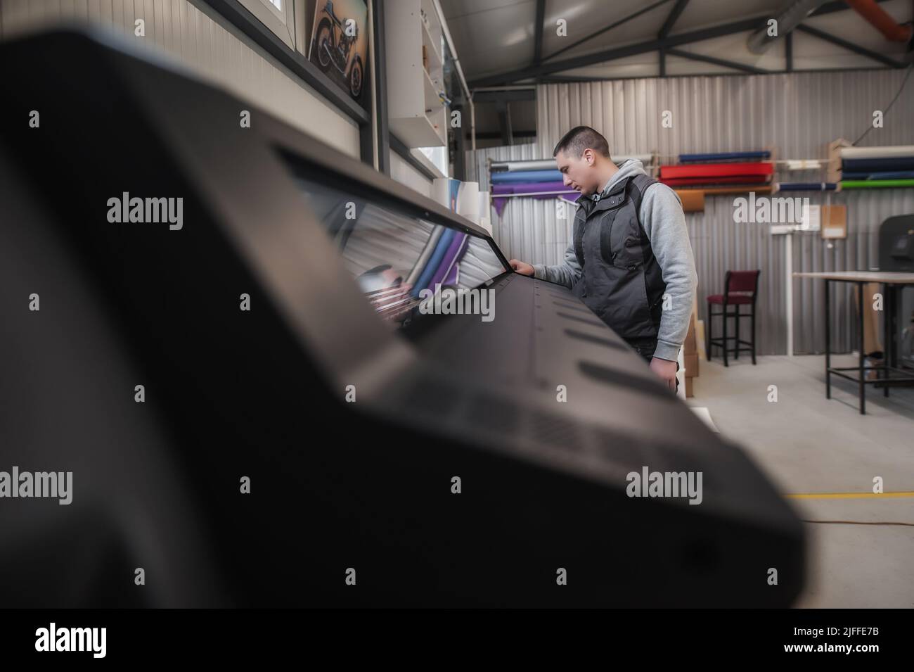 Techniker, der den ein- und Ausgabestatus auf der Touchscreen-Monitorstation auf der Vorderseite des Digitaldruckereibüros überprüft Stockfoto