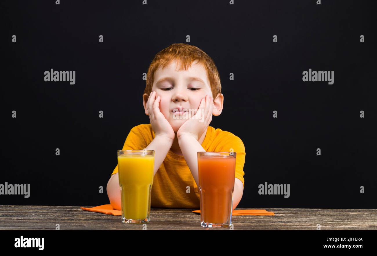 Der Junge trinkt bitteren und sauren Saft aus roter Grapefruit, der Saft ist nicht köstlich und
