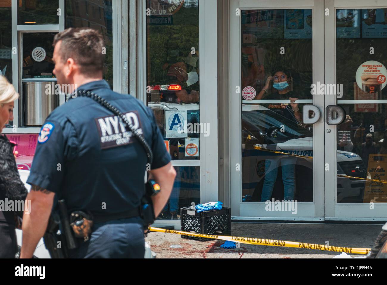 2. Juli 2022: Mitarbeiter von Dunkin' Donuts schauen aus dem Schaufenster, nachdem vor ihr in Manhattans Lower East Side, New York, ein Mann geschossen wurde Stockfoto