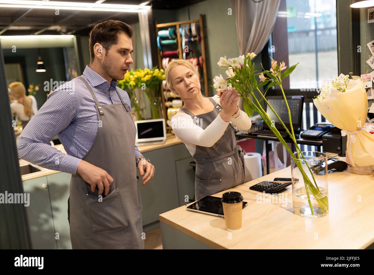 Ein Blumengeschäft Besitzer lehrt ihre Praktikantin, wie man einen frischen Blumenstrauß zu montieren. Stockfoto