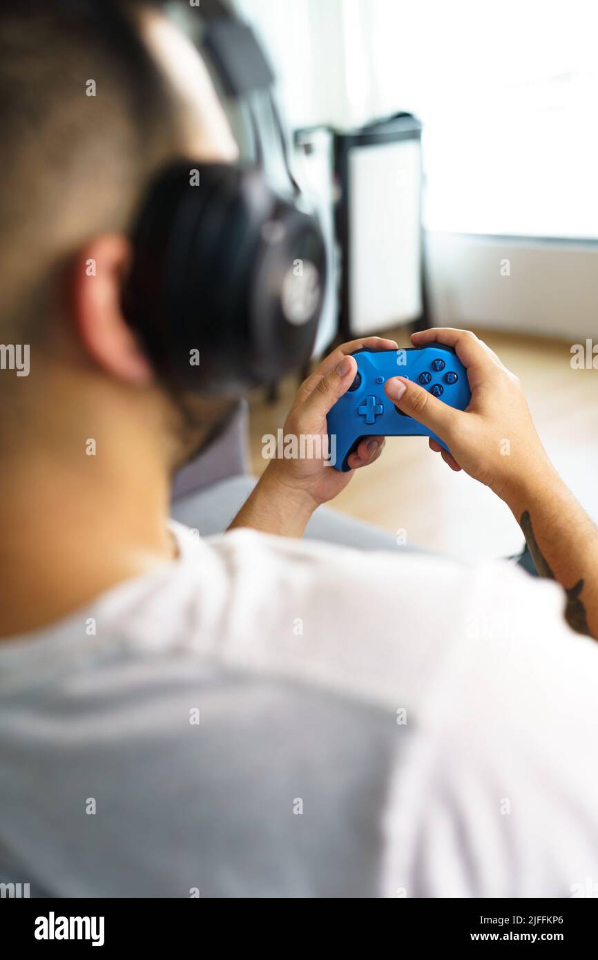 Spielen mit einem Video-Controller, während der Klang mit Kopfhörern hören, Gamer Spaß mit moderner Technologie, Hobbys Stockfoto