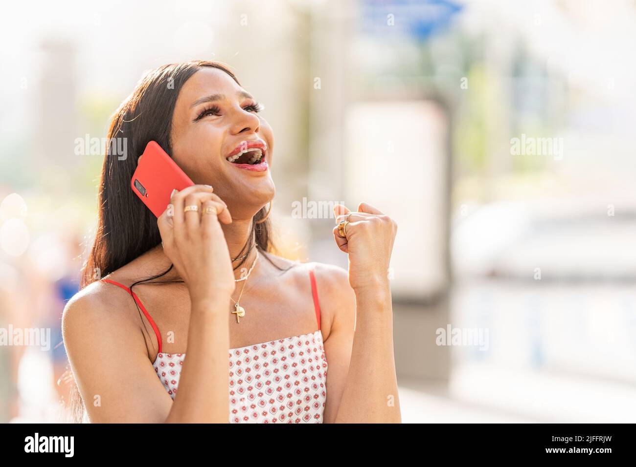 Trans-Frau feiert Nachrichten, während sie mit dem Handy im Freien spricht Stockfoto