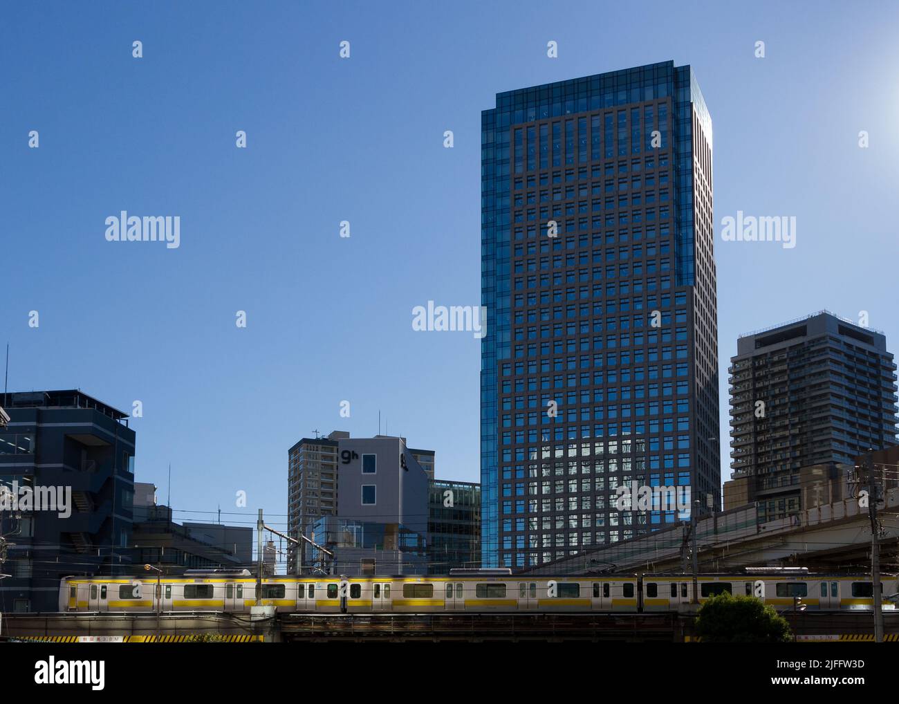 Ein Zug der Serie E231-500 auf der Chuo-Soba-Linie fährt vor hohen Gebäuden in Iidabashi, Tokio, Japan. Stockfoto