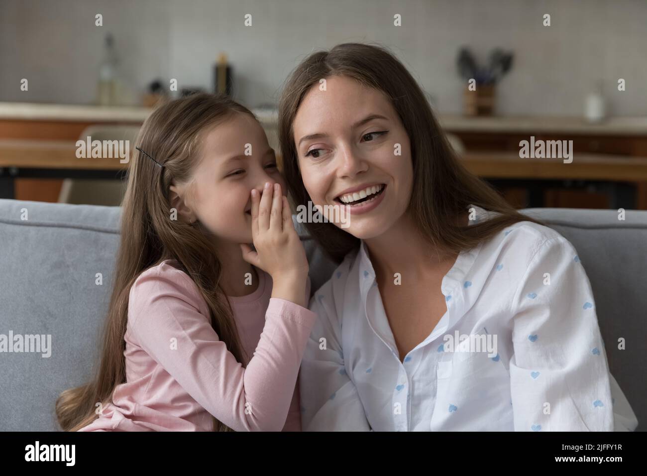 Nette kleine Tochter teilen Geheimnis auf Mütter Ohren Stockfoto