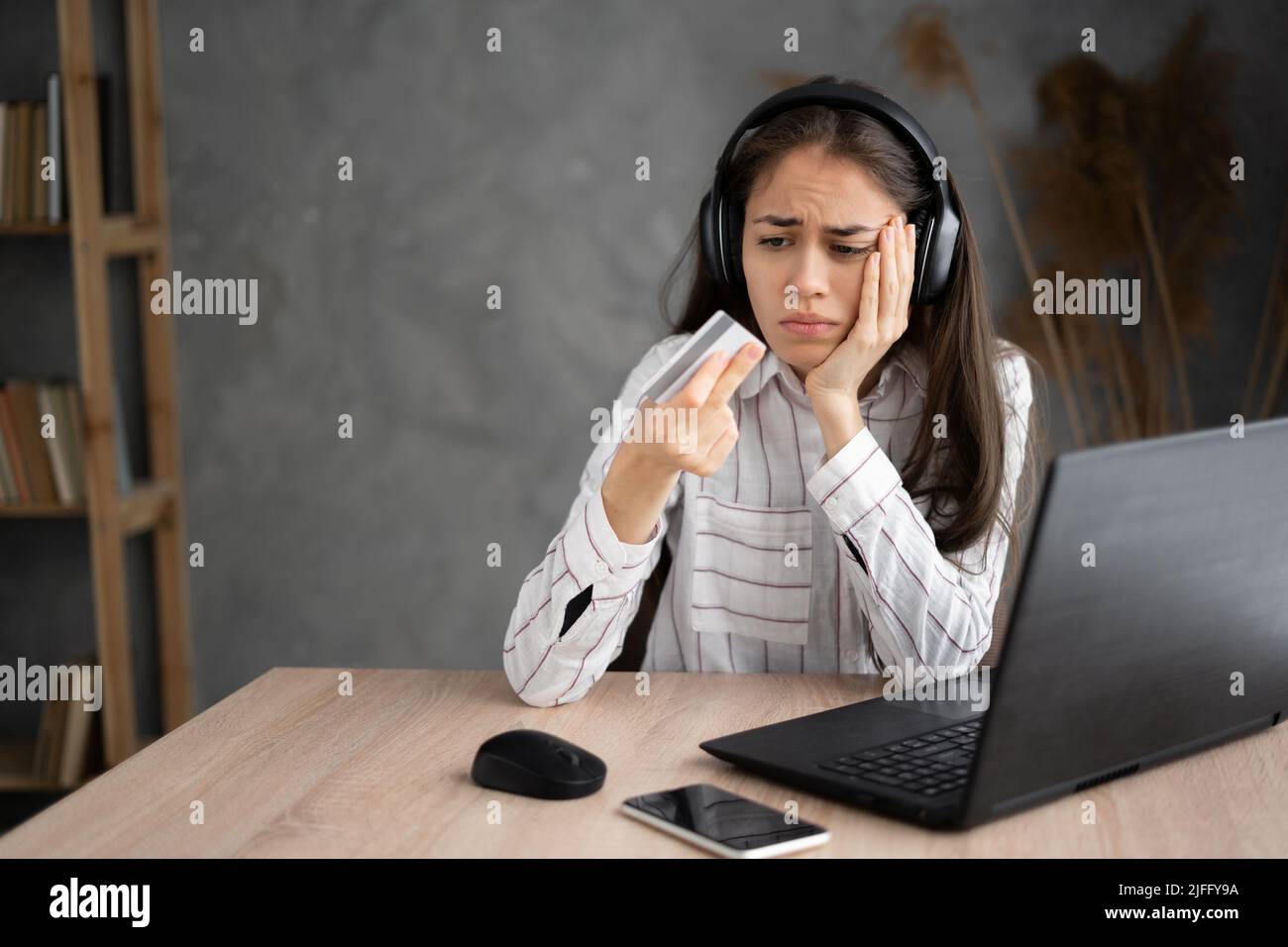 Gelegenheitskäufer besorgt über Probleme beim Online-Kauf mit einer Kreditkarte und einem Laptop in einem kleinen Büro oder zu Hause. Karte mit Mädchen Probleme mit der Zahlung Stockfoto