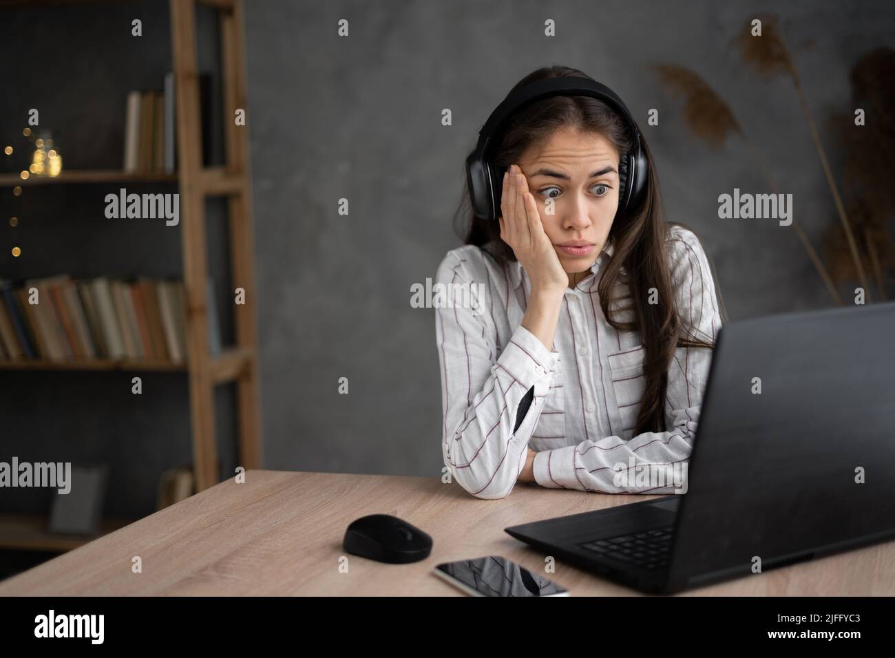 Junge hispanische Frau, die einen beängstigenden Film sieht, sich vor Angst versteckt, Online-Filmservice, Frau in Panik fühlt sich unglücklich gescheitert Stockfoto