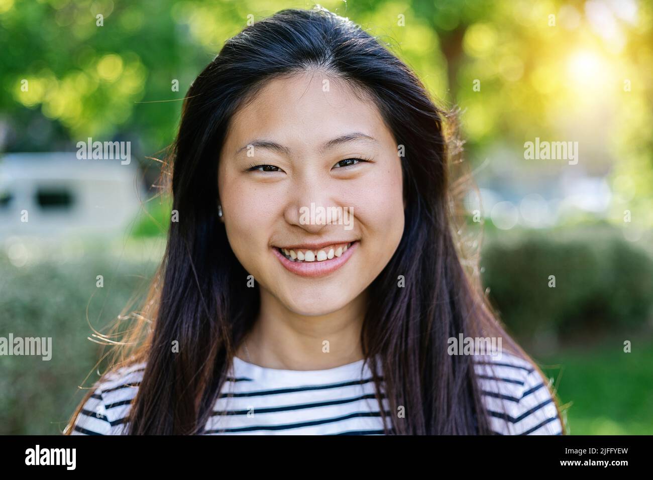 Glückliche junge asiatische Frau lächelt vor der Kamera im Freien Stockfoto