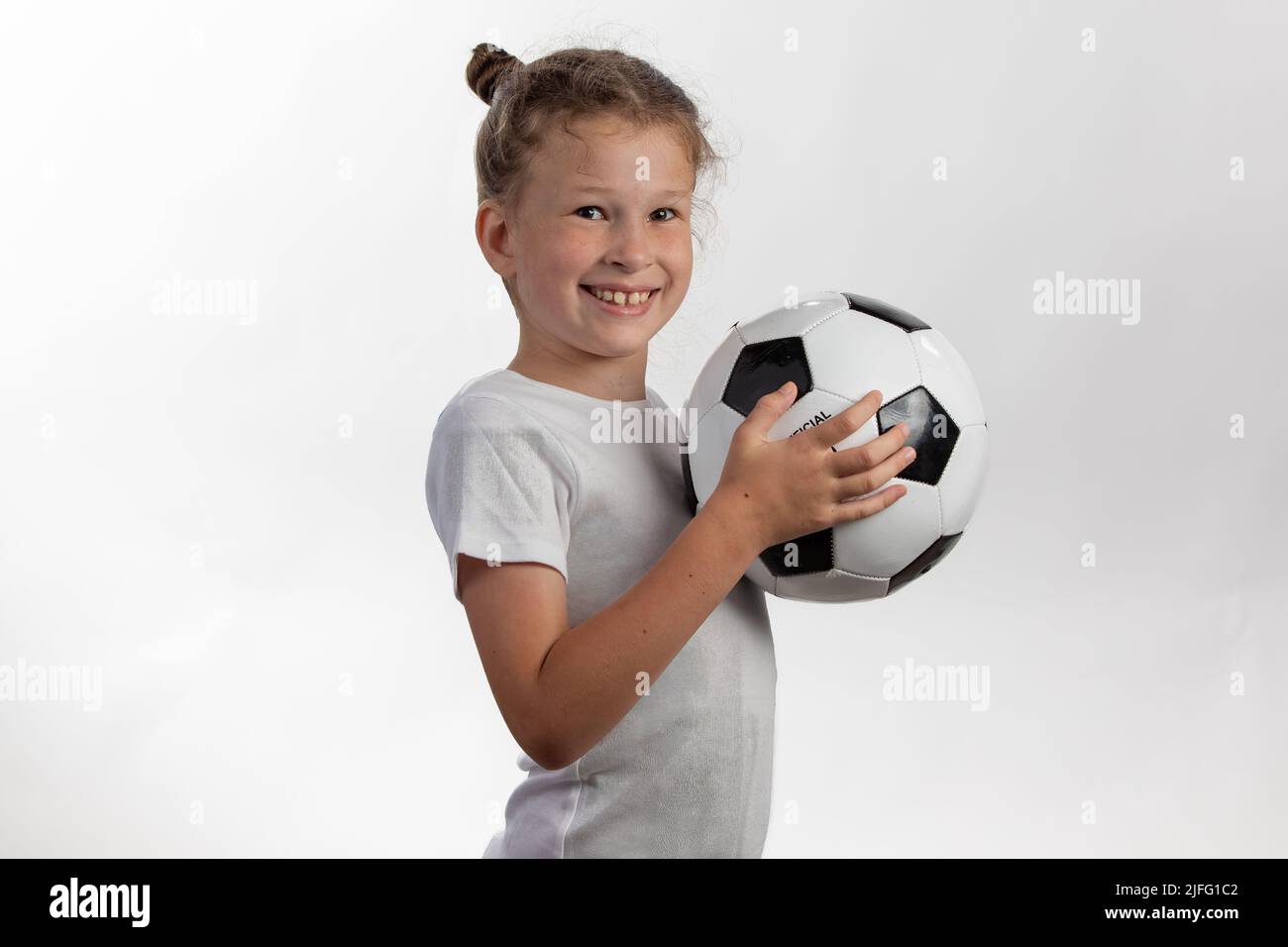 Soccer Kid Holding Soccerball - laden Sie zu einer Jugend-Fußball-Liga Stockfoto