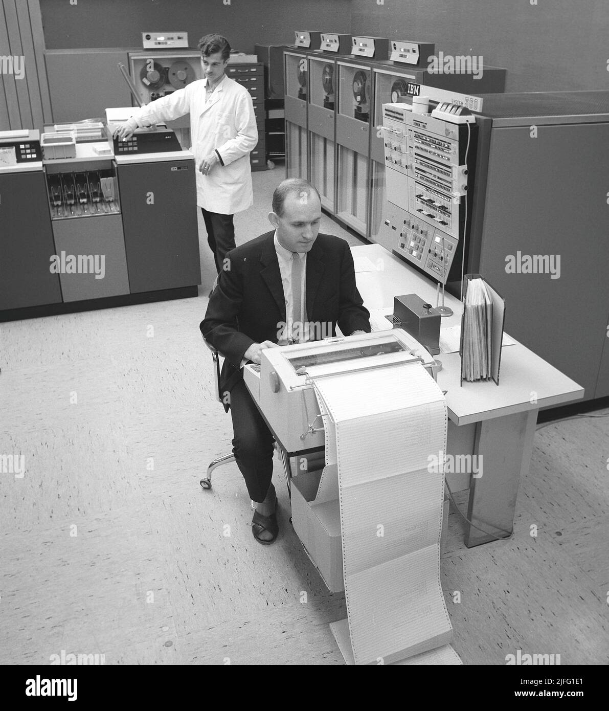 In der 1960s. Innenraum eines Raumes mit Computern und Menschen, die mit ihnen umgehen und Informationen registrieren und lesen. Auf einem Schild über dem Mainframe-Computer steht IBM 360. IBM System 360 wurde häufig in der amerikanischen Fernsehserie Mad Men gesehen. Bild aufgenommen 1965 Kristoffersson Ref. DY125-10 Stockfoto