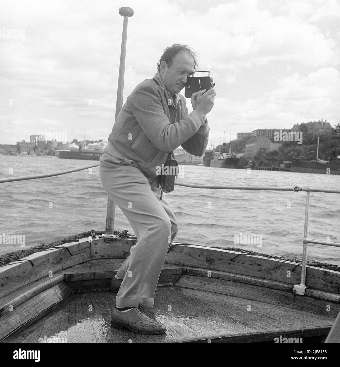 In der 1950s. Ein Mann dreht mit einer Amateurfilmkamera. Der Film wurde dann entwickelt und auf einem Filmprojektor auf einer zusammenklappbaren Leinwand zu Hause gezeigt. Der Film hatte keinen Ton. Die Filmkameras waren nicht batteriebetrieben und man musste sie wie eine Uhr aufwickeln, damit sie funktionieren. Stockholm Schweden 1950 Kristoffersson Ref. AZ53-6 Stockfoto