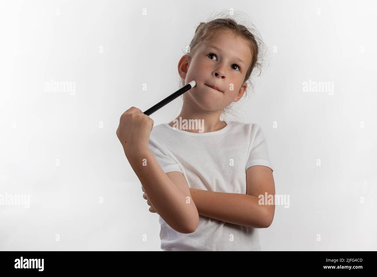 Mädchen Magierin mit einem Zauberstab in den Händen - junge Magierin denkt, was als nächstes zu tun - vor weißem Hintergrund Stockfoto