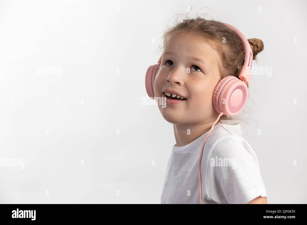 Nahaufnahme Porträt eines jungen Mädchens mit rosa Kopfhörern, um Musik zu suchen Stockfoto