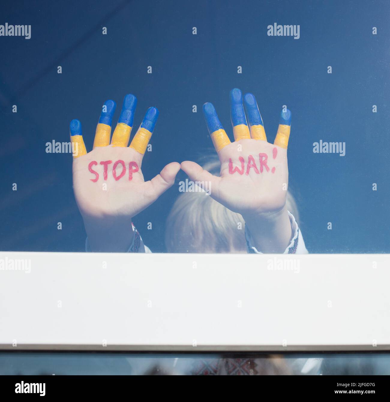 Kinderhände auf Glas Fenster, in gelb-blauer Farbe gemalt, Inschrift in rot STOPPEN KRIEG. Russlands Invasion der Ukraine, Kinder gegen Krieg. Bleib Stockfoto