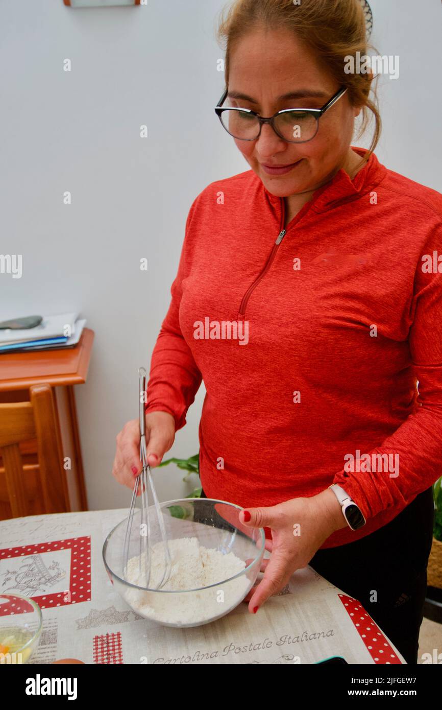 Eine Frau, die ein Mehl in einer Schüssel mischt, um Kuchen zu Hause zu machen Stockfoto