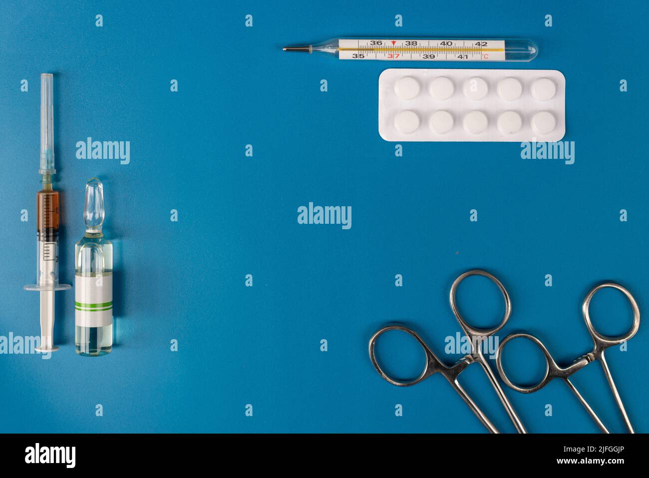 Operationsinstrument, elektronisches Thermometer und medizinische Kapseln auf blauem Hintergrund. Stockfoto