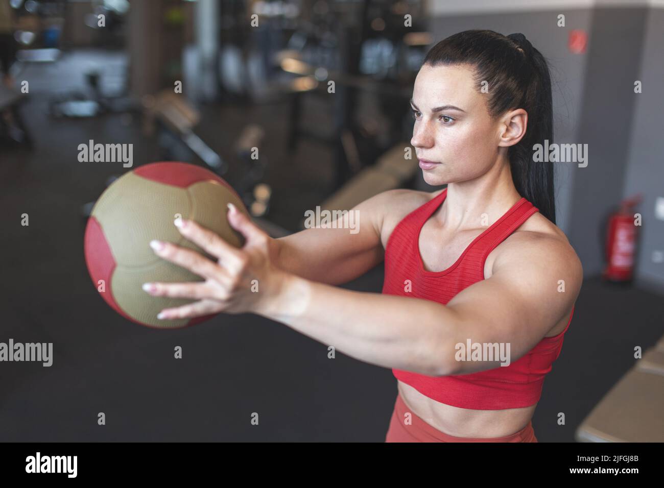 Junge kaukasische Frau, die Übung durch Medizinball im Fitnessstudio macht Stockfoto