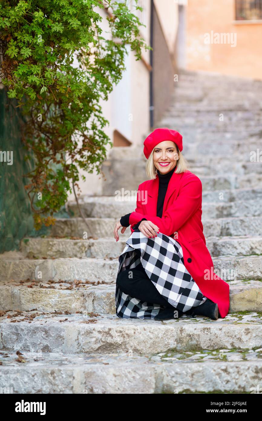 Glückliche anmutige Dame, die auf der Straße auf der Treppe sitzt Stockfoto
