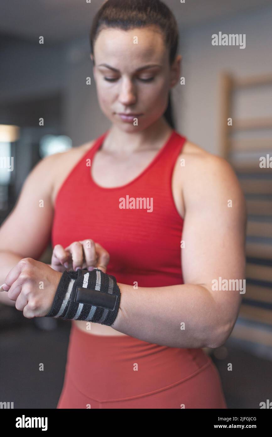 Junge kaukasische Frau legte in der Turnhalle selektiven Fokus auf Handgelenkwickel Stockfoto