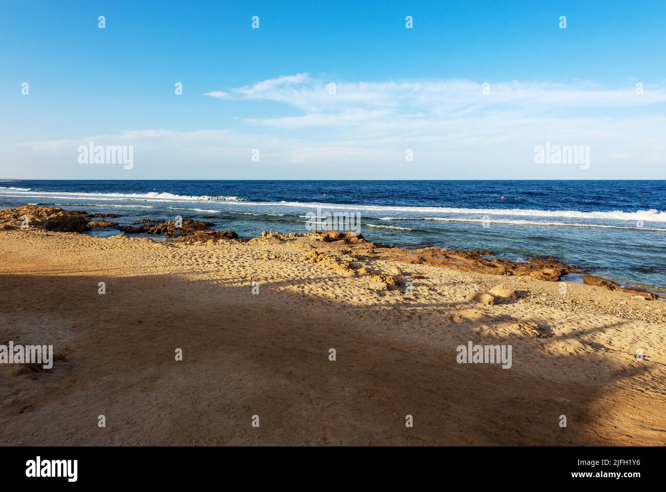 Sandstrand und wunderschöne Meereslandschaft des Roten Meeres in der Nähe von Marsa Alam, Ägypten, Afrika. Die Wellen brechen auf dem Korallenriff und der Klippe. Stockfoto