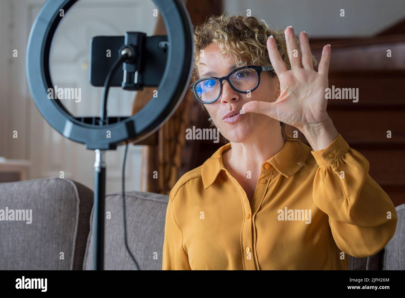 Personen, die Inhalte erstellen. Moderne Frau, die zu Hause mit einem Mobiltelefon und Ringlicht arbeitet und Inhalte für den Web-Kanal produziert. Digital und sma Stockfoto