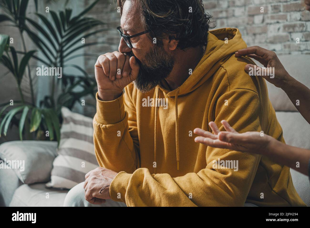 Trauriger und besorgter Mann schaut weg, während eine Frau seine Schulter berührt und versucht, mit ihm zu sprechen. Paar und Liebe Probleme. Schlechter Beziehungsmoment. Menschen Stockfoto