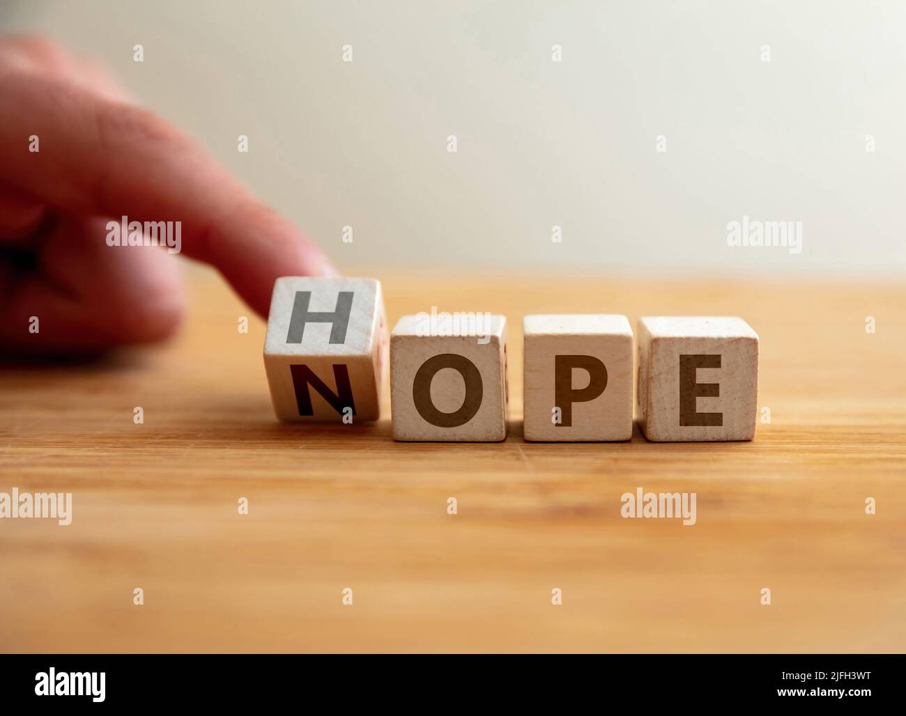 Hope or Nope Konzept. Finger kippt Buchstaben auf Holzwürfel und ändert das Wort Nope in Hoffnung. Botschaft zur Veränderung von Pessimismus zu Optimismus, negativ Stockfoto