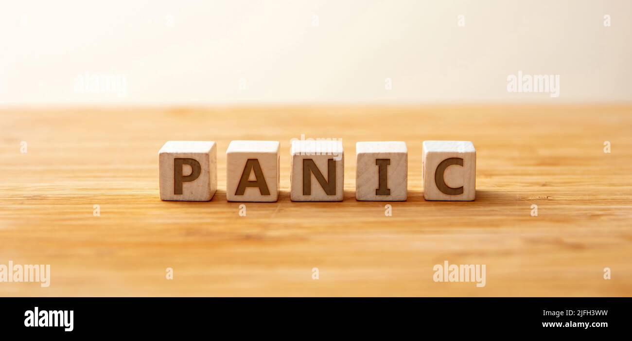 Panic Text auf Holzwürfel auf Holztisch Hintergrund. Plötzliche unkontrollierbare Angst oder Angst braucht eine psychische Gesundheitsversorgung. Metapher, Stress im Geschäft und Stockfoto