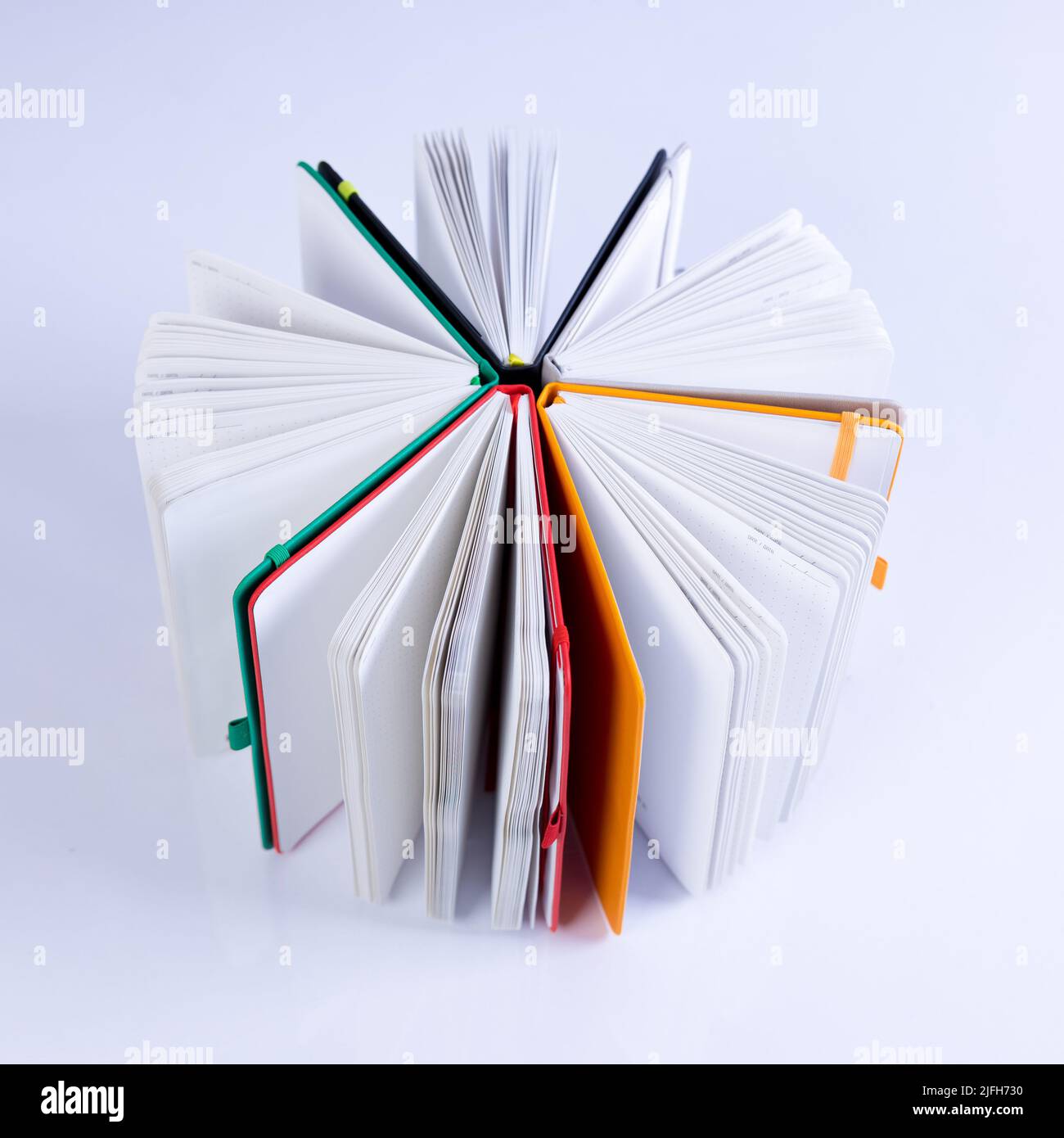 Farbenfrohe Zeitschriften, die wie eine Blume zusammengefügt sind. Schönes Studiofoto von Notebooks auf weißem Hintergrund. . Hochwertige Fotos Stockfoto
