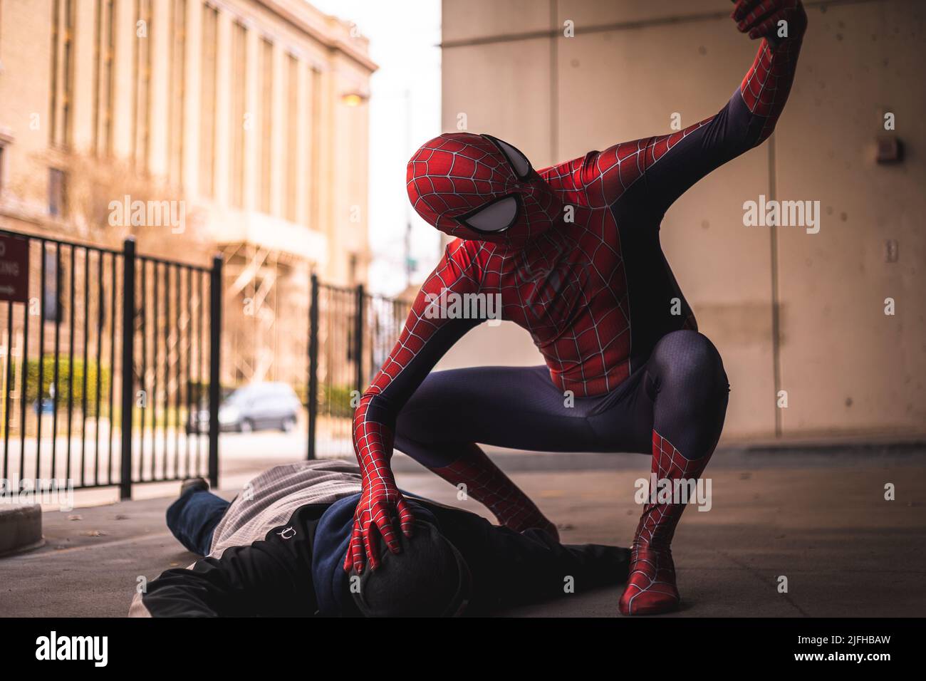 Lustige Szene mit einem Spider-Mann, der ein Selfie mit einem besiegten Bösewicht in der Innenstadt von Fort Worth in Texas, USA, macht Stockfoto