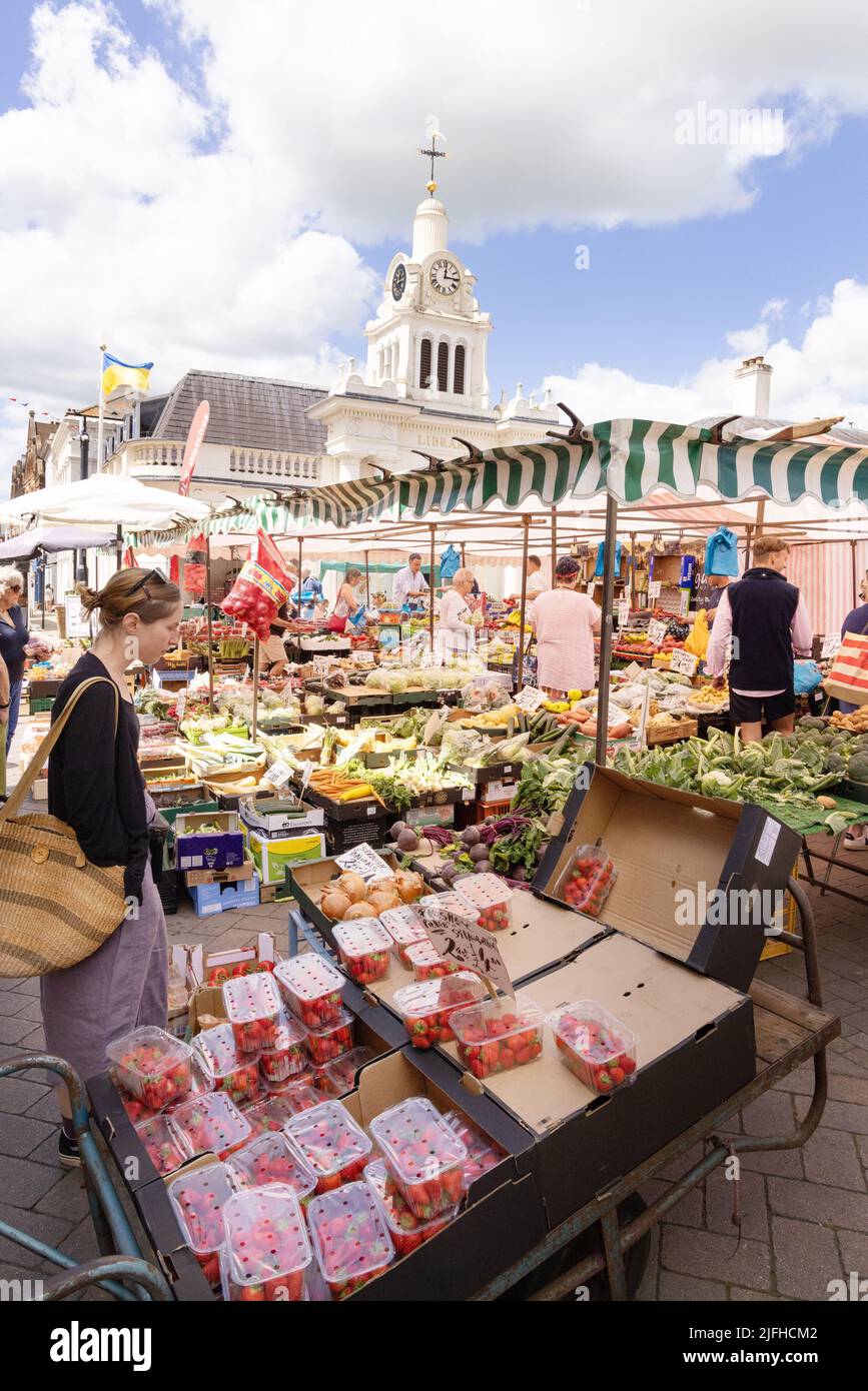 Frauen-Einkaufsmarkt Großbritannien; kaukasische Frau im Alter von 20s Jahren, die Obst an einem Obststand, Saffron Walden Market Square, Saffron Walden, Essex England, kauft Stockfoto