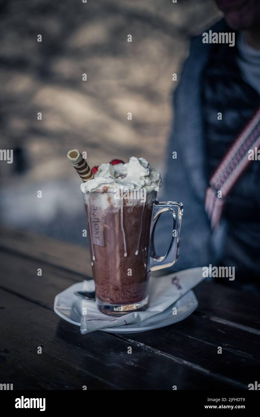 Ein Glas Kaffee mit Schlagsahne und Schokolade auf einem Holztisch Stockfoto