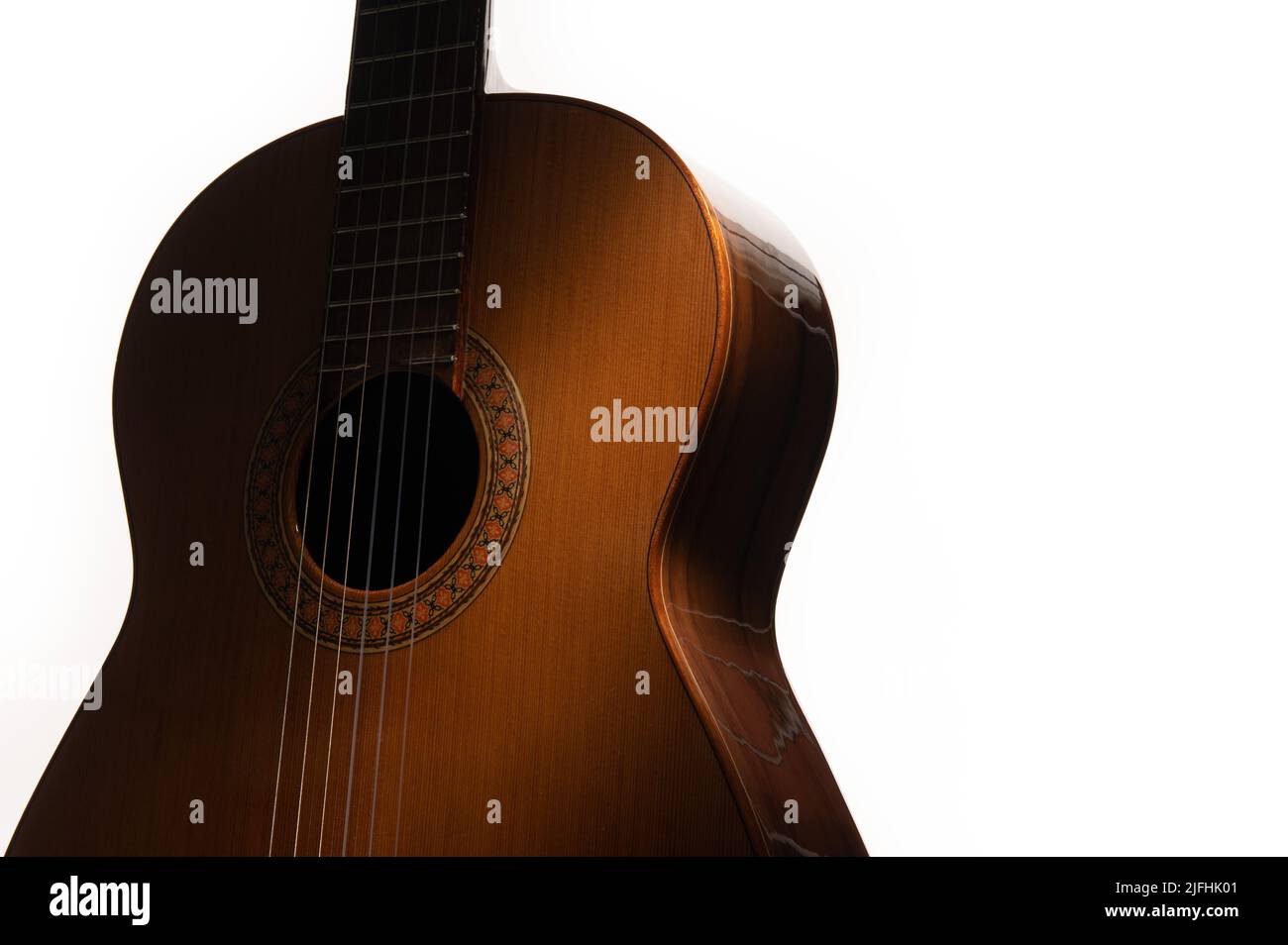 Spanische klassische Gitarre in Nahaufnahme, dramatisch beleuchtet auf weißem Hintergrund mit Kopierraum. Stockfoto